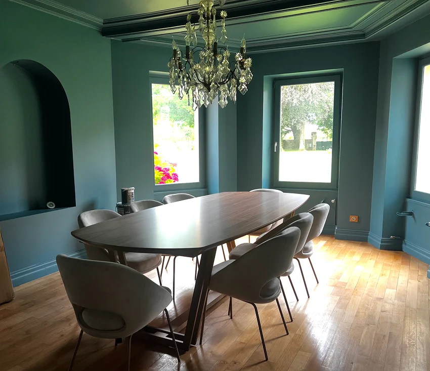 Salle à manger aux murs bleu-vert avec grande table en bois