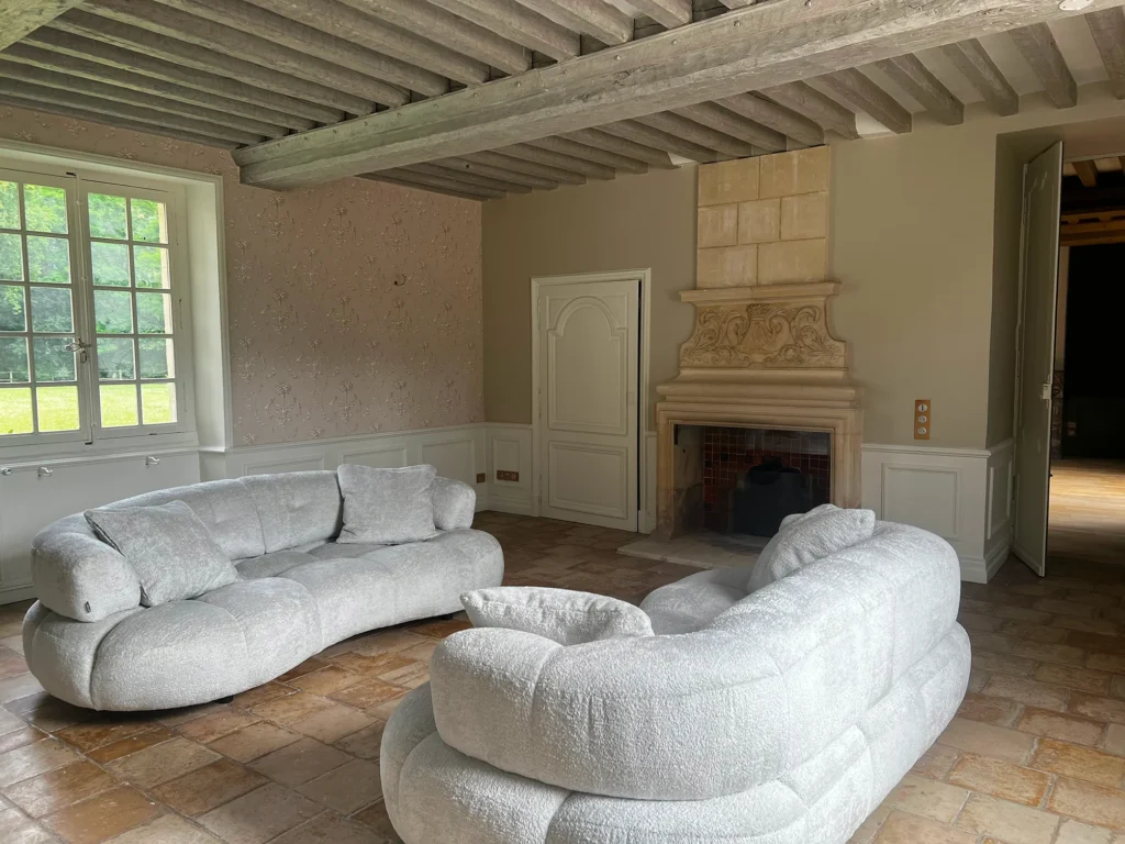 Salon d'un château en Normandie après travaux, cheminée en marbre et poutres