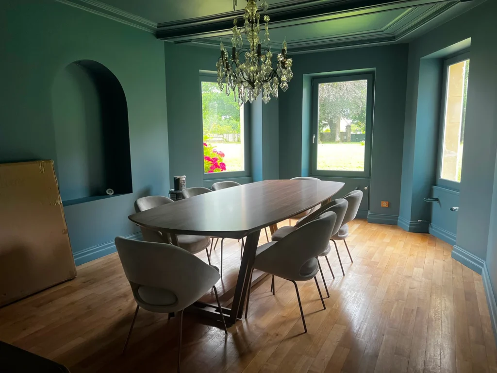 Salle à manger d'un château peinte en vert profond avec grande table et lustre