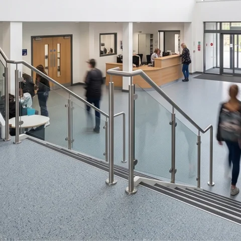 Escalier de lycée avec revêtement de sol neuf et garde-corps métallique