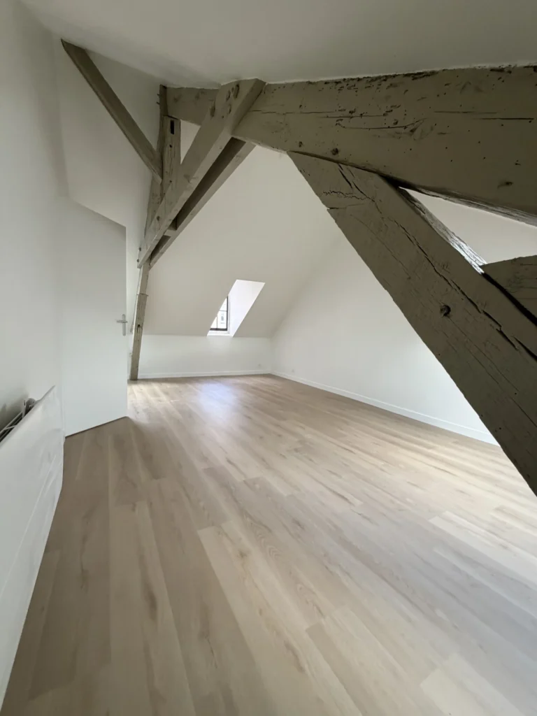 Charpente apparente conservée et sol stratifié après rénovation, Angers